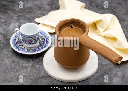 Türkischer Kaffee in einer irdenen Kanne auf dunklem Hintergrund. Geschmack der traditionellen türkischen Küche. Nahaufnahme Stockfoto