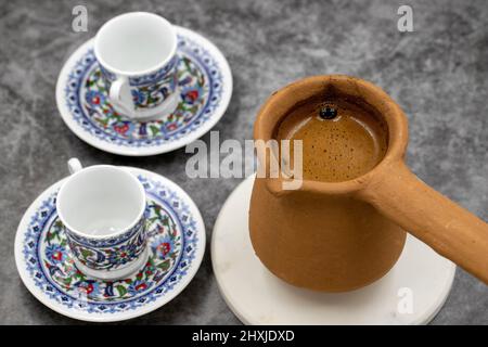 Türkischer Kaffee in einer irdenen Kanne auf dunklem Hintergrund. Geschmack der traditionellen türkischen Küche. Nahaufnahme Stockfoto