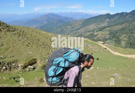 Seitenansicht eines männlichen Touristen, der einen Fallschirmrucksack trägt und im wunderschönen Berg Himachal Pradesh spazierengeht Stockfoto