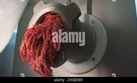 Konzept des Kochens . Clip. Ein Fleischwolf aus Metall, der eine bestimmte Menge Fleisch in Nahaufnahme fein reibt. Stockfoto