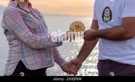 26 Wochen Schwangere mit einer Schwangerschaftskarte am Meer und Ehemann. Konzept für Schwangerschaftsfotoaufnahmen. Schwangerschaft und Elternschaft. Vater und Mutter. Stockfoto