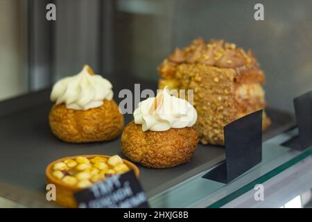 Verschiedene gebackene Shu-Kuchen, Torten und kiewer Kuchen im Glasvitrine im Bäckercafe. Gekühltes Gebäck liegt im Café auf dem Regal. Stockfoto