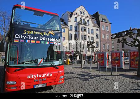 Düsseldorf (Burgplatz), Deutschland - März 9. 2022: Blick auf den Red Hop on and off Sightseeing Bus mit offenem Dach am sonnigen Wintertag, historisches Stadtbild b Stockfoto