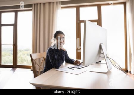 Profilbild glückliche junge indische Frau mit pc am Arbeitsplatz Stockfoto