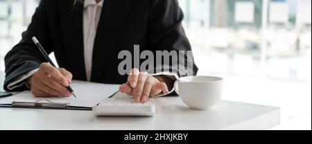 Ausschneiden Schuss der Buchhalterin Frau Handpresse auf Rechner und Schreiben einer Notiz für Finanzbericht oder Unternehmen Gewinn jährlich am Schreibtisch, Buchhalter Job machen Stockfoto