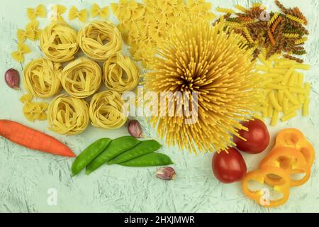 Verschiedene Nudelsorten auf dem Tisch. Verschiedene Arten von rohen Nudeln und Nudeln mit Gemüse. Kulinarisches Konzept der italienischen Küche. Collectio Stockfoto