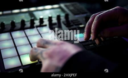 Nahaufnahme des djs, der mit der professionellen Drum-Maschine im Nachtclub arbeitet. Art. Junger Mann, der schnell auf die Knöpfe einer Beat-Maschine klopft. Stockfoto
