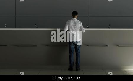 Minimalistisches Interieur einer Hotellobby mit Rezeption. HDR. Rückansicht eines Geschäftsmanns in weißem Hemd, der zur Rezeption ging und fragte Stockfoto