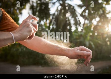 Prävention gegen Mückenstich in tropischen Destination. Mann, der Insektenschutzmittel auf seine Hand gegen Palmen auflegte. Stockfoto