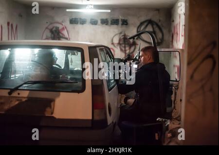 Hinter den Kulissen. Filmteam, das im Auto in einer Garage in der Halle eine Filmszene gedreht hat. Gruppenfilmproduktion eingestellt Stockfoto