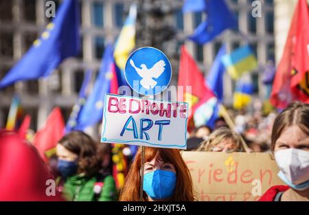 Frankfurt, Deutschland. 13. März 2022, Hessen, Frankfurt/Main: Ein Demonstrator hält ein Plakat mit einer Friedenstaube und der Aufschrift "bedrohte Arten", während sich Tausende Menschen unter dem Motto "Stoppt den Krieg! Frieden und Solidarität für die Menschen in der Ukraine versammelten sich vor der Alten Oper (mit Zoom-Effekt aufgenommen). Ein breites Bündnis von mehr als 50 Organisationen hatte in mehreren deutschen Städten zu Großdemonstrationen aufgerufen. Foto: Frank Rumpenhorst/dpa Quelle: dpa picture Alliance/Alamy Live News Stockfoto