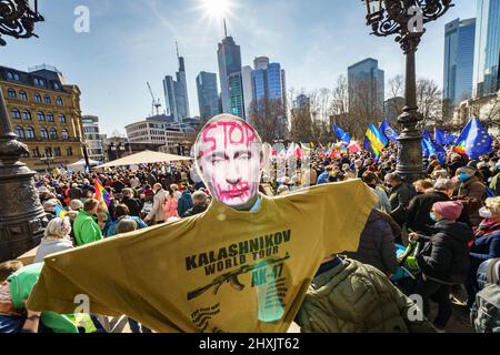 Frankfurt, Deutschland. 13. März 2022, Hessen, Frankfurt/Main: Ein Demonstrator hält ein Plakat mit dem russischen Präsidenten Putin mit der Aufschrift "Stop war" und ein T-Shirt mit der Aufschrift "Kalaschnikow World Tour". Tausende Menschen hatten sich unter dem Motto „Stoppt den Krieg! Frieden und Solidarität für die Menschen in der Ukraine versammelten sich vor der Alten Oper. Ein breites Bündnis von mehr als 50 Organisationen hatte in mehreren deutschen Städten zu Großdemonstrationen aufgerufen. Foto: Frank Rumpenhorst/dpa Quelle: dpa picture Alliance/Alamy Live News Stockfoto