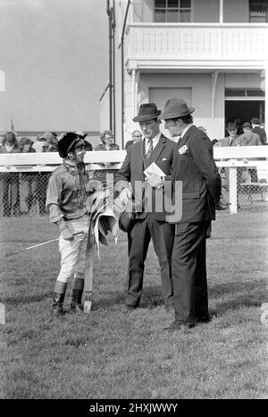 Jockey Willie Carson. „All the Queens Horses“. In West Ilsley steht Berks-Trainer Major W. R. Hern vor den 13 Pferden für die Queen. Von links nach rechts: Hintere Reihe Star Harbour; Circlet; Alma; Tartan Pimpernell; Dunfermline; Und Mary Fitton. Erste Reihe: Bewertung; Kette der Argumentation; Fife und Trommel; Herzog der Normandie; Rhyme Royal; Gesellig und Paintbrust. Der Mann 2. von rechts ist Stan Clayton, ehemaliger Jockey der Queen. 1977 77.-02213-008. April Stockfoto