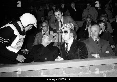 Ein Polizist im Gespräch mit Graham Taylor und Elton John, die das Fußballspiel beobachten, West Bromwich Albion gegen Watford. 25. Oktober 1977. Stockfoto