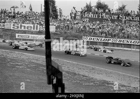 James Hunt (im Teco McLaren 2. aus dem rechts abfahrenden Bereich mit der Nummer 11) stürzt ab, gewinnt aber nach einem Neustart schließlich noch 1976 den britischen Grand Prix in Brands Hatch. Der britische Fahrer James Hunt war an einem ersten Eckunfall beteiligt, der die roten Fahnen hervorbrachte. Hunt fuhr sein beschädigtes Auto zurück zur Box, vollzog dafür jedoch keine volle Runde der Strecke, sondern fuhr auf der Cooper Straight durch eine Zufahrtsstraße. Die Beamten erklärten, dass Hunt, da er nicht auf dem Kurs gewesen war, als die rote Flagge geschwenkt wurde, nicht am Neustart teilnehmen durfte. Diese Nachricht führte zu mu Stockfoto