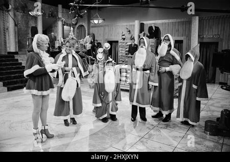 Die Besetzung von „wird dir serviert?“ Während der Dreharbeiten zu ihrer Weihnachtsshow. Im Bild von links nach rechts John Inman (Mr Humphries), Wendy Richard (Miss Brahms), Trevor Bannister (Mr Lucas), Frank Thornton (Captain Peacock), Nichola Smith (Mr Rumbold) und Arthur Brough (Mr Grainger). 6.. Dezember 1976. Stockfoto