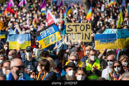 Stuttgart, Deutschland. 13. März 2022. Zahlreiche Menschen demonstrieren im oberen Schlossgarten gegen den russischen Militäreinsatz in der Ukraine. Unter anderem halten die Teilnehmer Schilder mit der Aufschrift „Stop Putin“ in den Händen. Quelle: Christoph Schmidt/dpa/Alamy Live News Stockfoto