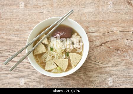 Vietnamesische Reisnudeln oder Pho mit Wurst in Scheiben schneiden und Schweinefleisch in einer Suppe auf einer Schüssel hacken Stockfoto