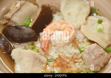 Gekochter Reis mit Meeresfrüchten und Schweineknochen in klarer Suppe auf einer Schüssel mit würziger Sauce Stockfoto