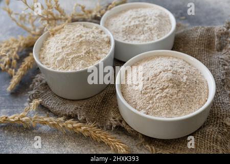 Lebensmittel und Backzutat. Weizenmehl grob aus Vollkorngetreide, Weizenkleie und Weizenmehl auf grauem Steingrund. Stockfoto