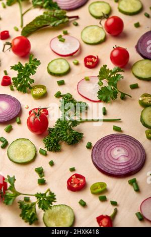 Scheiben von Gurken, Zwiebeln, Grün, Tomatenkirsche beliebte Gewürze Konzept. Draufsicht auf frisches schönes Gemüse auf weichem gelben Hintergrund verstreut, Stockfoto