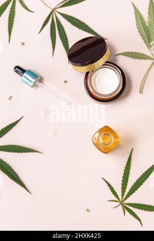 SPA Bio-Beauty-Produkt. Konzept Der Pflanzlichen Alternativen Medizin. Cannabis-Kosmetikcreme, Gesichtsserum und Hanfblätter auf beigem Hintergrund. Draufsicht f Stockfoto