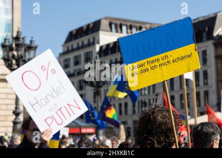 13. März 2022, Hessen, Frankfurt/Main: Demonstranten halten Schilder mit den Aufschrift "0 Prozent Handel mit Putin" und "Ich würde lieber einfrieren - als mich schämen!" ab. Unter dem Motto „Stoppt den Krieg! Frieden und Solidarität für die Menschen in der Ukraine", ein breites Bündnis von mehr als 50 Organisationen, hatte zu Großdemonstrationen in mehreren deutschen Städten aufgerufen. Foto: Hannes P. Albert/dpa Stockfoto