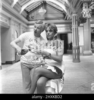 John Inman (Mr Humphries) und Wendy Richard (Miss Brahms) aus der Besetzung der BBC-TV-Situationskomödie sind Sie hier zu sehen, um den Erfolg ihrer Sommershow zu feiern. August 1976 Stockfoto