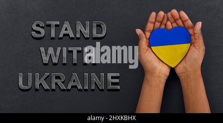 Stehe Mit Der Ukraine. Frau mit Herz in den Farben der ukrainischen Flagge gemalt Stockfoto