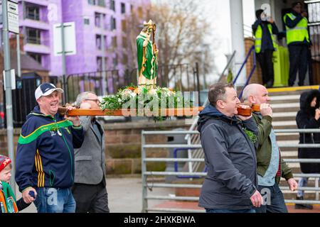 Warrington, Hes. 13. März 2022. Der Warrington Irish Club ist Gastgeber des Services und des Starts der St. Patrick's Day Parade. Dies ist die erste Parade seit dem Start von COVID. Beginnend um 10,30 Uhr morgens vom Irish Club in Orford Lane zum ‘River of Life' in der Bridge Street im Stadtzentrum, wo ein kurzer Gottesdienst abgehalten wurde, um an den Jahrestag des Bombenanschlags von Warrington zu erinnern. Es regnete, sobald die Parade begann und dann kam die Sonne heraus. Eine Statue des heiligen Patrick wird durch die Stadt getragen. Quelle: John Hopkins/Alamy Live News Stockfoto