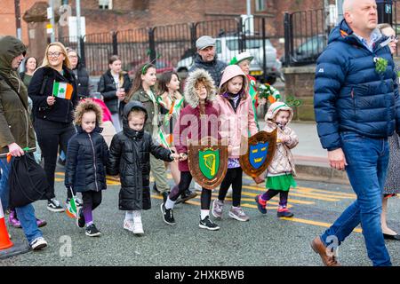 Warrington, Hes. 13. März 2022. Der Warrington Irish Club ist Gastgeber des Services und des Starts der St. Patrick's Day Parade. Dies ist die erste Parade seit dem Start von COVID. Beginnend um 10,30 Uhr morgens vom Irish Club in Orford Lane zum ‘River of Life' in der Bridge Street im Stadtzentrum, wo ein kurzer Gottesdienst abgehalten wurde, um an den Jahrestag des Bombenanschlags von Warrington zu erinnern. Es regnete, sobald die Parade begann und dann kam die Sonne heraus. Kinder nahmen an der Parade Teil. Quelle: John Hopkins/Alamy Live News Stockfoto