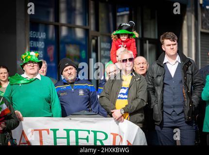 Warrington, Hes. 13. März 2022. Der Warrington Irish Club ist Gastgeber des Services und des Starts der St. Patrick's Day Parade. Dies ist die erste Parade seit dem Start von COVID. Beginnend um 10,30 Uhr morgens vom Irish Club in Orford Lane zum ‘River of Life' in der Bridge Street im Stadtzentrum, wo ein kurzer Gottesdienst abgehalten wurde, um an den Jahrestag des Bombenanschlags von Warrington zu erinnern. Es regnete, sobald die Parade begann und dann kam die Sonne heraus. Während des Gedenkdienstes sitzt ein Kind auf den Schultern ihres Vaters. Quelle: John Hopkins/Alamy Live News Stockfoto