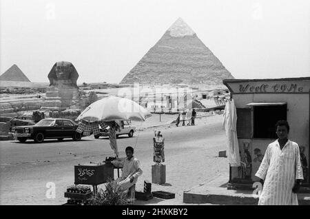 Zwei lokale ägypter, die hier an der Großen Pyramide und Sphinx von Gizeh gesehen wurden, verkaufen Postkarten und Cola an Touristen 29.. Mai 1976 Stockfoto