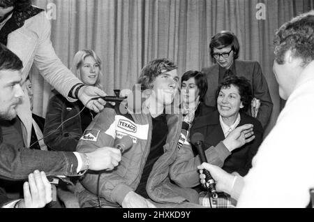 James Hunt, der neue Weltmeister im Motorsport, wurde von einem Helden begrüßt, als er heute Morgen von Japan aus den Flughafen Heathrow erreichte. Der 29-jährige McLaren Formel-1-Fahrer wurde von einem Großteil seiner Familie und Freundin Jane Birbeck begrüßt. Das Bild zeigt, wie James mit den Medien spricht. Seine Mutter, die Frau, sitzt zu seiner Linken im dunklen Mantel. Seine Schwester Georgina, Sally und sein Schwager Philip Jones (verheiratet mit Sally) sitzen dahinter. (Nicht 100 % der rechte, außer Philip Jones) Bild aufgenommen 26. October1976 Stockfoto