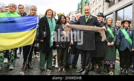 London, Großbritannien. 13. März 2022. Micheál Martin, irischer Taoiseach (Premierminister), führt vor der Londoner St. Patrick's Day Parade mit einem Schal in ukrainischen Farben, Dr. Debbie Weekes-Bernard, stellvertretende Bürgermeisterin, Gemeinschaften und soziale Gerechtigkeit zu seiner Linken, seine Frau Mary neben ihr, Und Pandemie-Schlüsselarbeiter, die als Großmarschall für die Parade geehrt wurden. Kredit: Imageplotter/Alamy Live Nachrichten Stockfoto