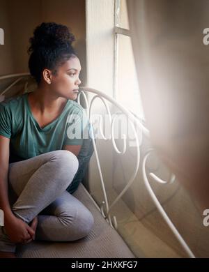 Sie hatte eine tolle Aussicht von ihrem Schlafzimmer. Hochwinkelige Aufnahme einer jungen Frau, die auf ihrem Bett sitzt. Stockfoto