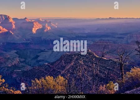 Wenn die ersten Sonnenstrahlen des Tages am Südrand des Grand Canyon eintreffen, wird der Nordrand durch diese Lichtstrahlen aus dem Osten deutlich hervorgehoben. Stockfoto