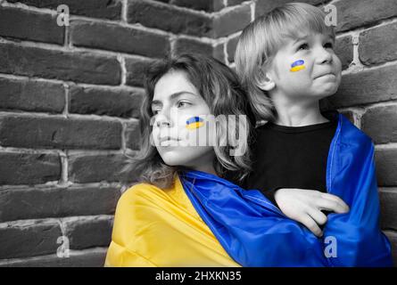 Junge und junge Frau mit ukrainischer Flagge. Farbakzent gelb und blau. Familie, Einheit, Unterstützung, nationale Unabhängigkeit. Kinder der Ukraine gegen die Stockfoto