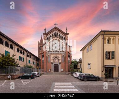 Cavallermaggiore, Italien - 12. März 2022: Kirche Santa Maria della Pieve im eklektischen gotischen Stil (Anfang 1900s), in der Via Roma, mit Sonnenuntergang am Himmel Stockfoto