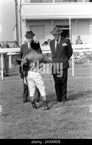 Jockey Willie Carson. „All the Queens Horses“. In West Ilsley steht Berks-Trainer Major W. R. Hern vor den 13 Pferden für die Queen. Von links nach rechts: Hintere Reihe Star Harbour; Circlet; Alma; Tartan Pimpernell; Dunfermline; Und Mary Fitton. Erste Reihe: Bewertung; Kette der Argumentation; Fife und Trommel; Herzog der Normandie; Rhyme Royal; Gesellig und Paintbrust. Der Mann 2. von rechts ist Stan Clayton, ehemaliger Jockey der Queen. 1977 77.-02213-006. April Stockfoto