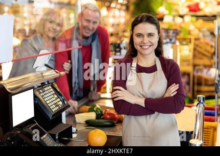Porträt einer schönen jungen Kassiererin, die vor der Kamera lächelt Stockfoto