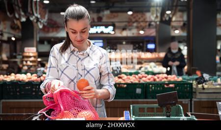 Eine junge Frau wählt Früchte in einem Supermarkt. Stockfoto