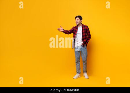Porträt eines glücklichen jungen Mannes, der in einem gelben Studio posiert Stockfoto