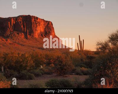 Sonnenuntergangsbilder am Superstition Mountain in Arizona und Umgebung. Die untergehende Sonne taucht die Gegend in goldene Rottöne. Stockfoto