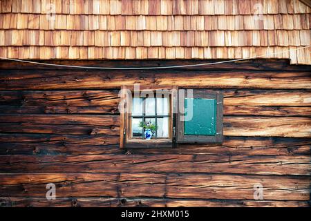 Detail einer alten Holzhütte mit Schindeln, Fenster, Rollläden und Holzbalken Stockfoto