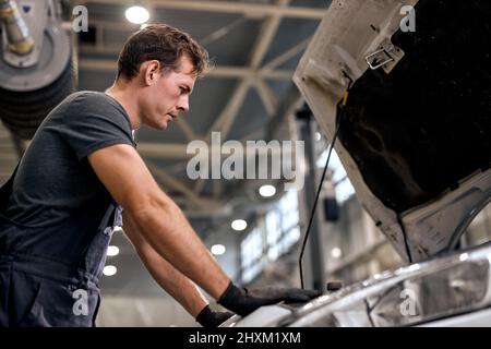 Automechaniker bei der Durchführung von Auto-Reparatur-Service und Wartungsarbeiter Reparatur Fahrzeug. Service und Wartung Auto-Check. Gut aussehend ernst kaukasischen Euro Stockfoto