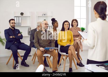 Die Geschäftscoach-Frau spricht bei der Besprechung im Büro vor einer kleinen Gruppe von Geschäftsleuten. Stockfoto