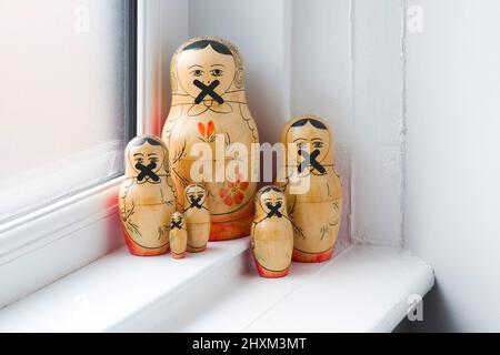 Die Familie der russischen Puppen in einer Gruppe auf einer Fensterbank mit durchgestrichenen Mündern, damit sie nicht sprechen können Stockfoto