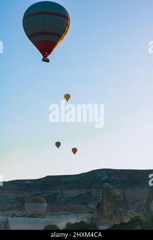 Heißluftballons bei Sonnenaufgang in Kappadokien vertikales Foto. Aktivitäten in Kappadokien Konzept. Reise in die Türkei Hintergrundbild. Stockfoto