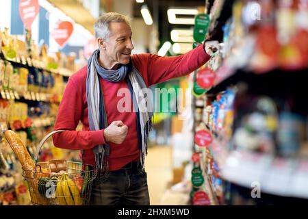 Positiv attraktiver Senior bei der Auswahl von Waren im Laden Stockfoto